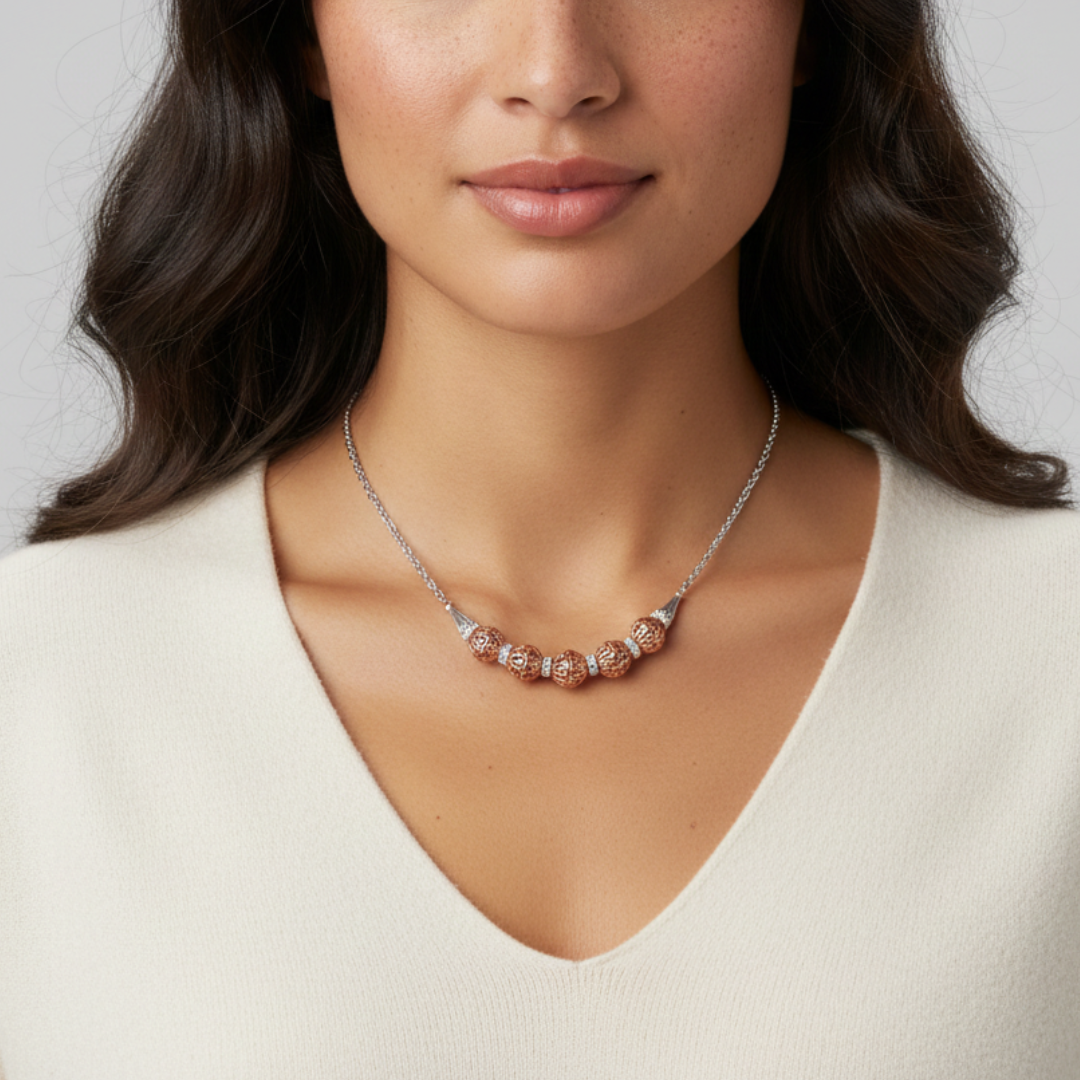 Woman wearing a silver necklace with rose gold accents on a neutral background