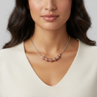 Woman wearing a silver necklace with rose gold accents on a neutral background