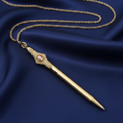 Decorative gold pen and red cameo pendant with chain on a blue fabric background