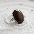 Carnelian Gemstone Austrian Crystal Oval Ring resting on fine white sand