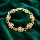 Gold tone Prestige Textured Link Crystal And Stone Bracelet on a green fabric background