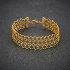Gold bracelet with a mesh textured design on a dark gray background