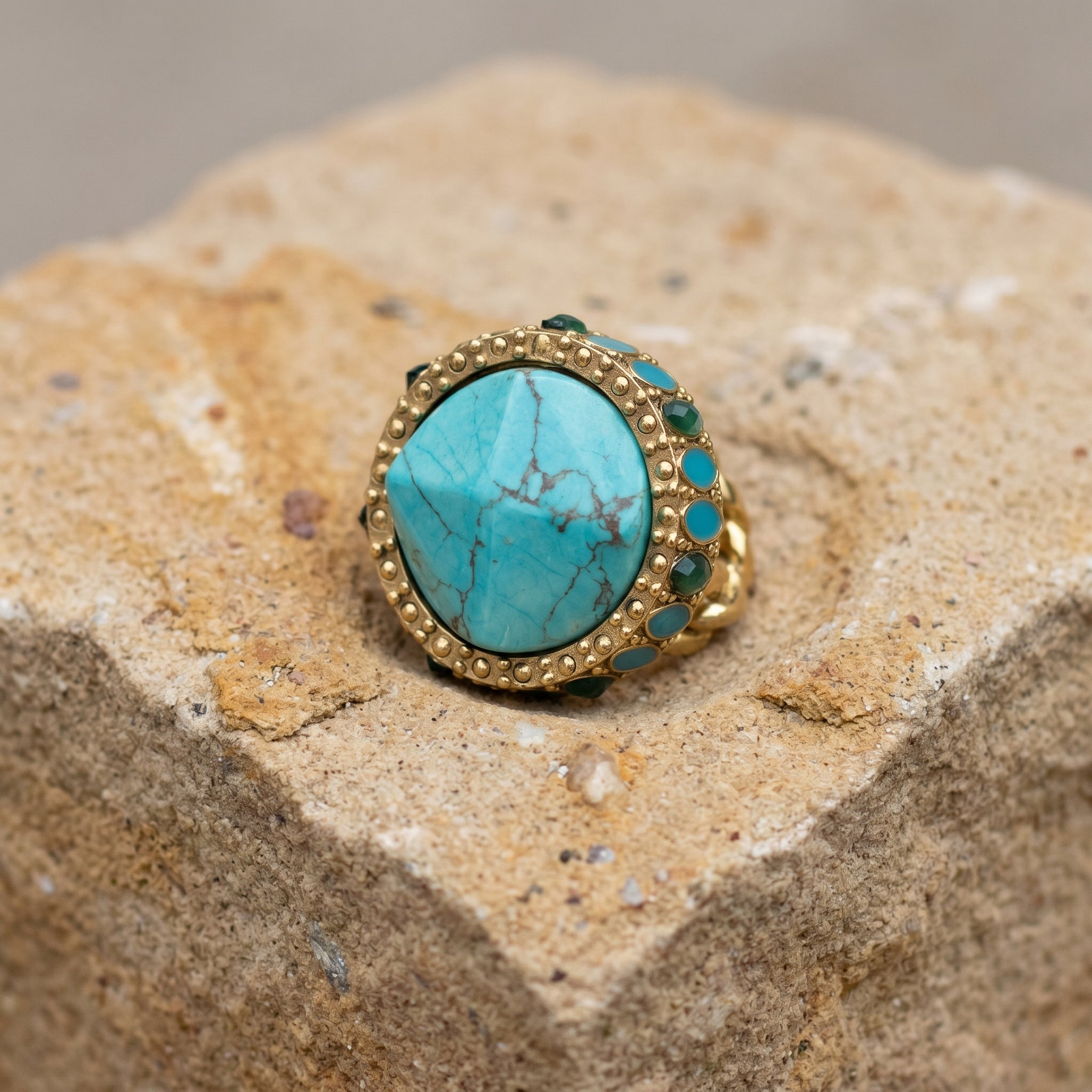Gold ring with turquoise stone on a textured stone surface