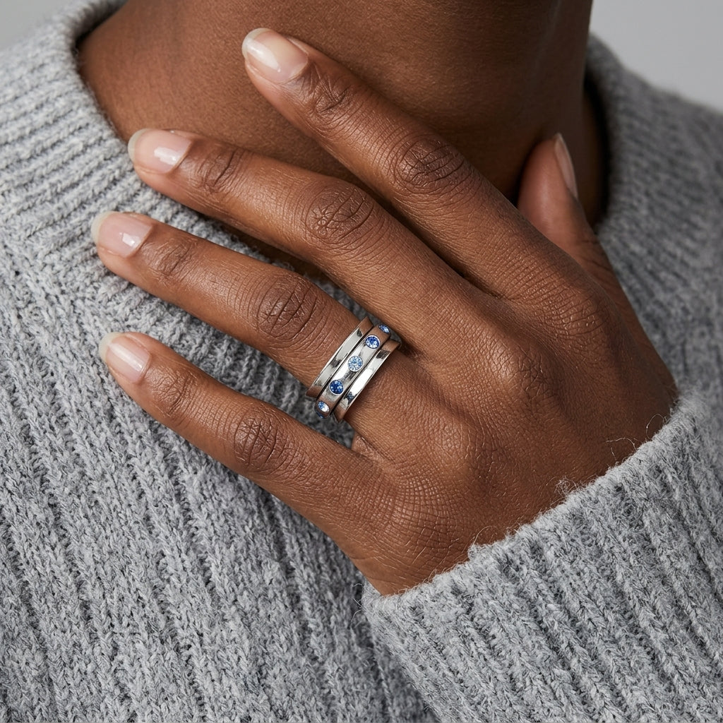 A close-up of a person's hand resting on their chest, wearing a Blue Aqua Marine Crystal Anxiety Spinner Ring