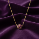 Gold necklace with a purple crystal pendant on a purple fabric background