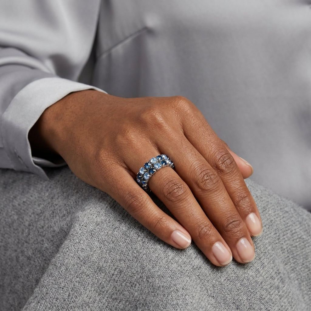 Blue crystal stretch ring on a woman's finger who is wearing a grey outfit