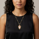 Woman wearing a black sleeveless top with a Victorian Reflections Carnelian & Ivory Cameo Faux Pearl Accent Necklace