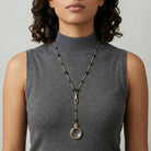 Black Bead Magnifying Glass Drop Necklace worn by a woman in a gray top