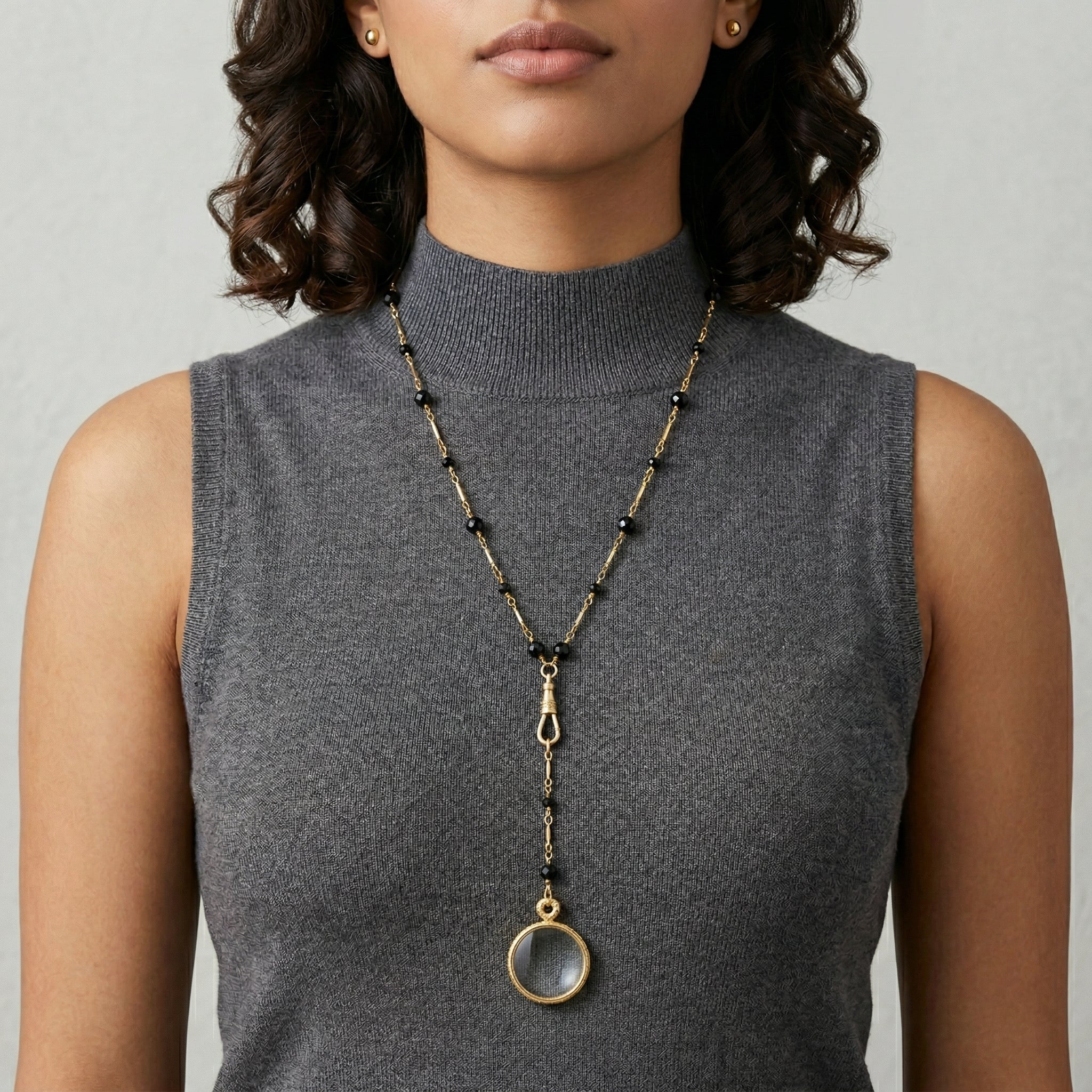 Black Bead Magnifying Glass Drop Necklace worn by a woman in a gray top