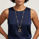 Filigree Chain Round Magnifying Glass Pendant Necklace worn by a woman in a sleeveless navy blue top
