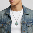 Man wearing a denim jacket and white shirt with a turquoise horse pendant necklace