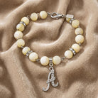 Mother Of Pearl Crystal Initial Charm Bracelet resting on light-colored fabric