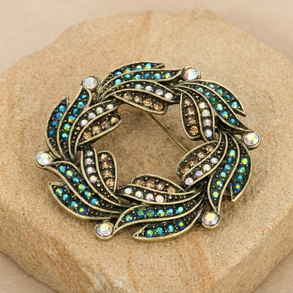 Peacock Plumage Blue Iridescent AB Glass Stone Wreath Brooch on a textured stone surface