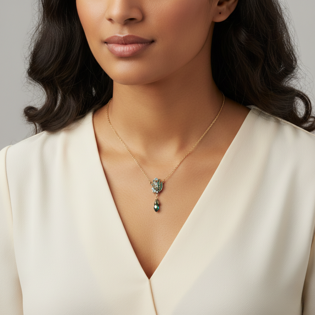 Woman wearing a gold necklace with a Peacock feather pendant against a neutral background.