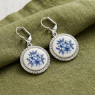 Round Blue Willow earrings with lever back closures resting on olive green linen