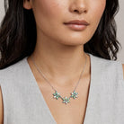 Peacock Plumage Blue Iridescent AB Glass Flower Necklace worn by a woman against a neutral background