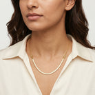Woman wearing a gold necklace with a plain background