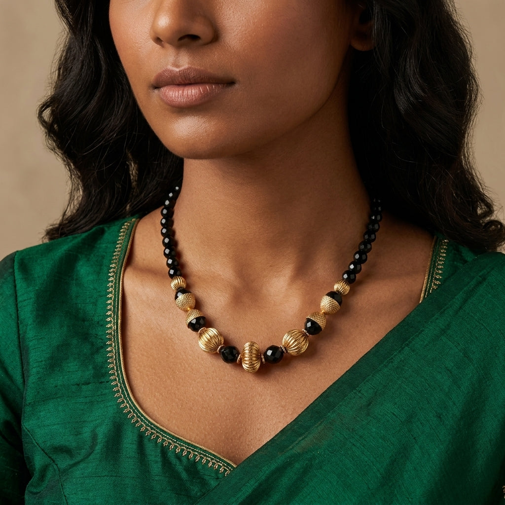 Woman wearing a black and gold beaded necklace with a green dress