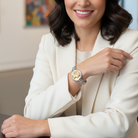 Woman wearing a white blazer and a bracelet with a Grecian cameo, smiling.