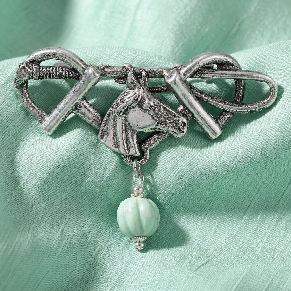 Horse Head & Stirrups Turquoise Gemstone Pin on a green fabric background