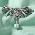 Horse Head & Stirrups Turquoise Gemstone Pin on a green fabric background