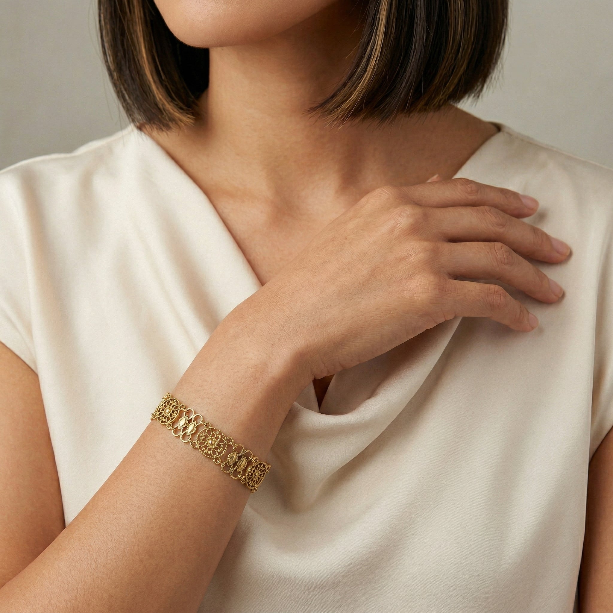 Woman wearing a gold tone Meso Round Intricate Filigree Link Bracelet