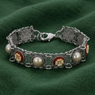Floral Link Faux Pearl & Ivory Flower Stone Bracelet on a green fabric background