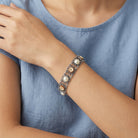 Close-up of a person wearing a decorative Floral Link Faux Pearl & Ivory Flower Stone Bracelet
