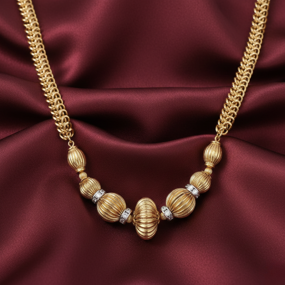 Gold-dipped necklace with beads on a burgundy satin background