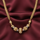 Gold-dipped necklace with beads on a burgundy satin background