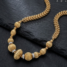 Corrugated Bead Crystal Accent Twisted Link Necklace on a black stone surface