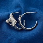 Pewter tone Etch Floral Horse Head Hoop Earrings displayed on a textured blue fabric background.