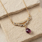 Cheshire Crystal Teardrop Collar Pendant Necklace resting on beige stone