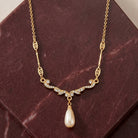 Edwardian Teardrop Faux Pearl Crystal Necklace 16" + 3" Extender displayed on a dark reddish-brown stone surface.