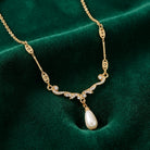 Edwardian Teardrop Faux Pearl Crystal Necklace resting on green fabric