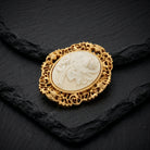 Filigree Oval White Flower Cameo Pin resting on black stone surface