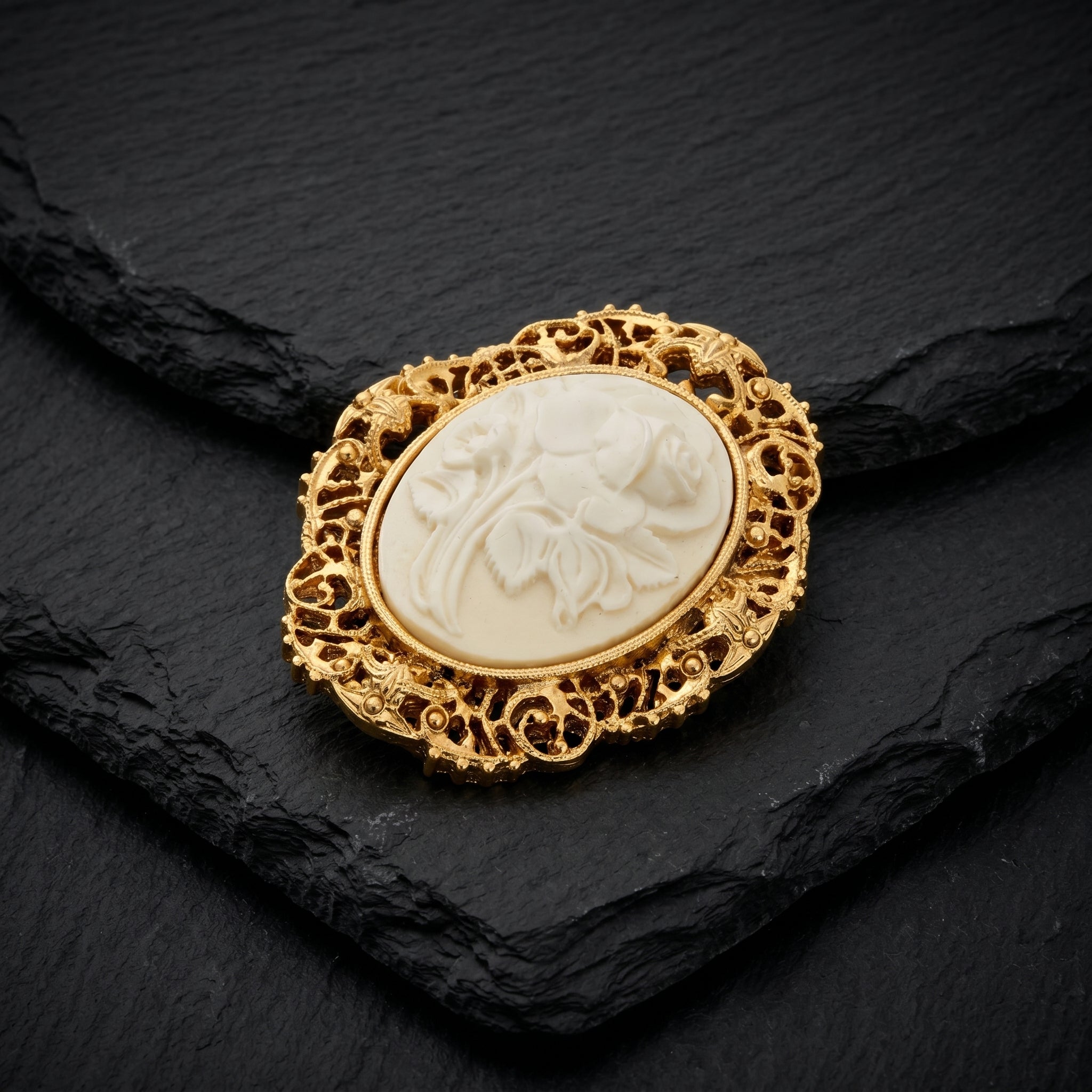 Filigree Oval White Flower Cameo Pin resting on black stone surface