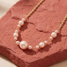 Rosabella Raspberry & Champagne Faux Pearl Necklace on a textured pink surface