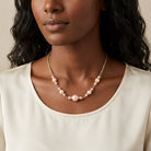 Woman wearing a Rosabella Raspberry & Champagne Faux Pearl Necklace with a white crew neck top 