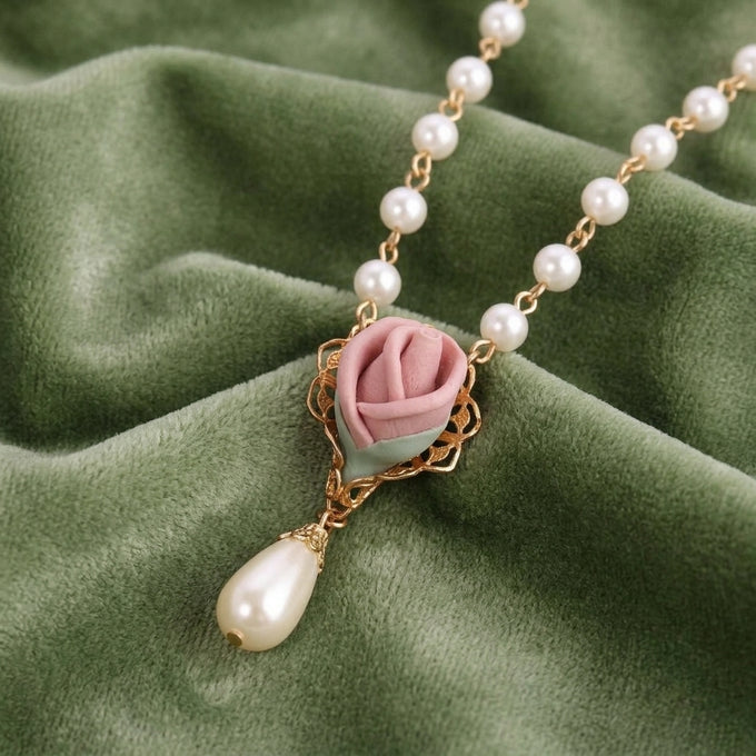 Pink Porcelain Rose Bud Faux Pearl Pendant Necklace on a green fabric background