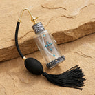 Antiqued Cross Light Blue Crystal Glass Atomiser Perfume Spray Bottle resting on brown sandstone surface