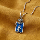 Pewter Dog Blue Enamel 'Save a Life' Pendant on a yellow fabric background.