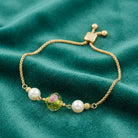 Bel Fiore Pink Glass Bead Faux Pearl Adjustable Bracelet resting on teal fabric