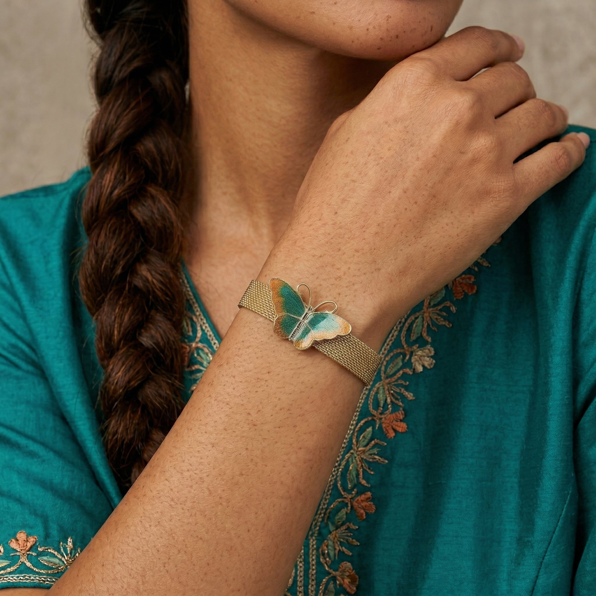 Woman wearing a gold tone Metamorphic Butterfly Weave Chain Bracelet on her wrist