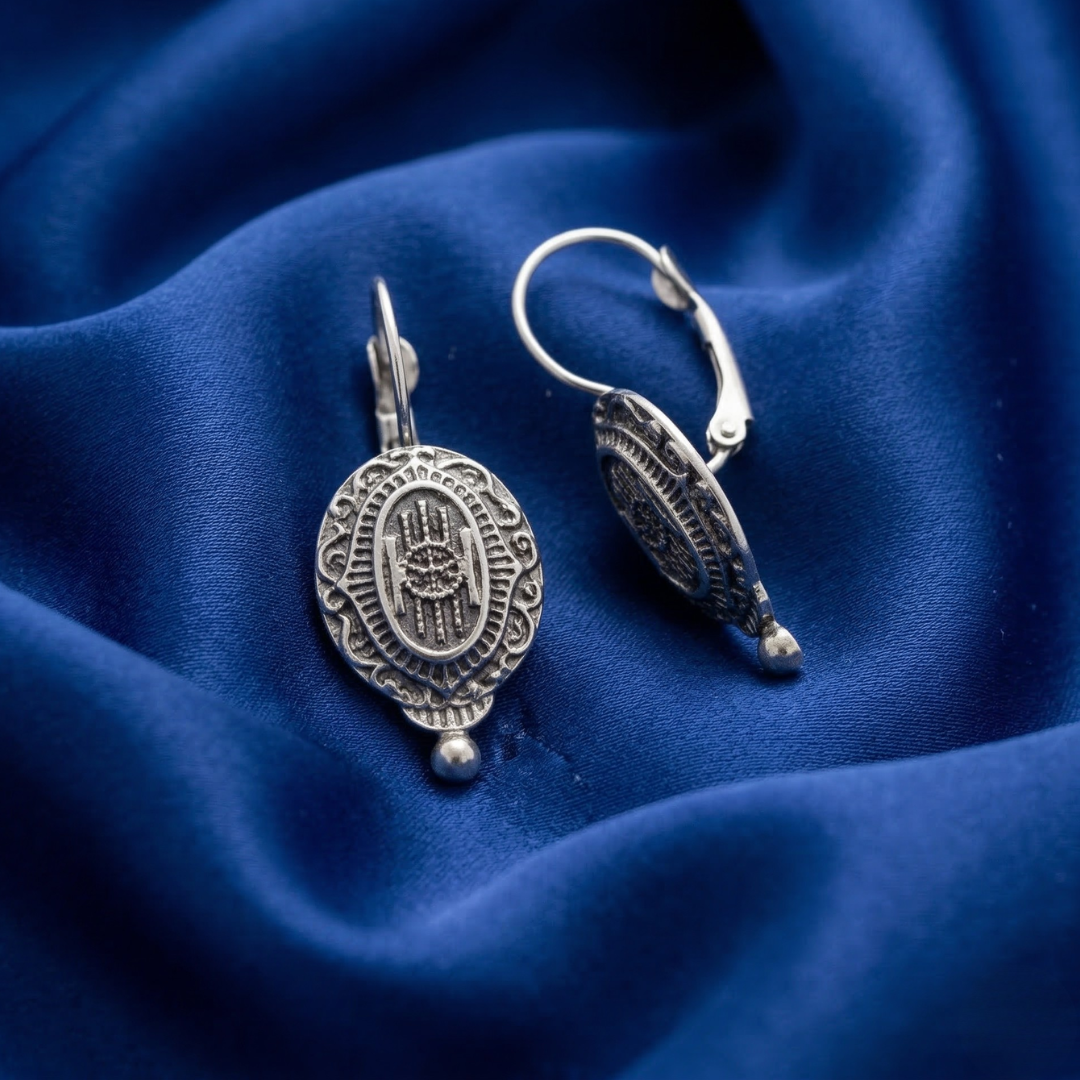 Silver Baroque Insignia Oval Drop Earrings on blue satin fabric