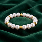 Aurelia Glass Faux Pearl Stretch Bracelet resting on dark green fabric