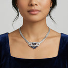 Woman in a blue dress wearing our Genevieve Aura Dark Blue Crystal Pendant Necklace