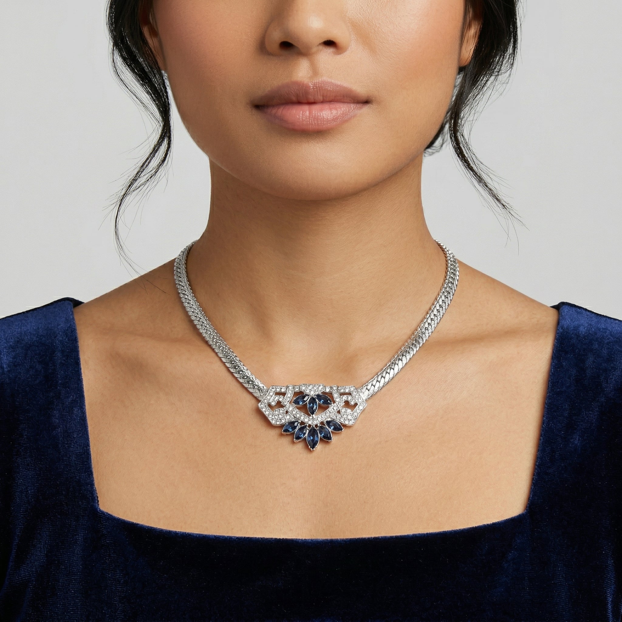 Woman in a blue dress wearing our Genevieve Aura Dark Blue Crystal Pendant Necklace