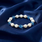 Aquamarine Crystal Mother Of Pearl Stretch Bracelet resting on dark blue satin fabric
