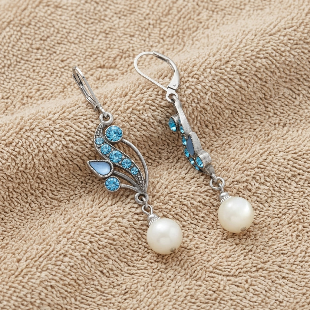 Aquamarine Crystal Mother Of Pearl Dangle Earrings displayed on a textured beige fabric background.